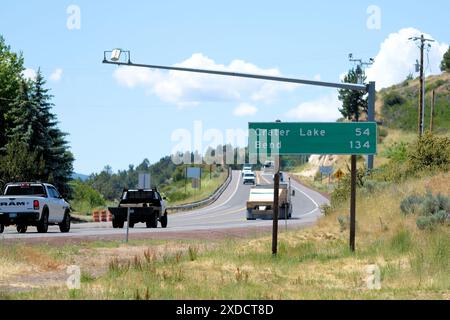 Sign on Highway 97 in Central Oregon alerting traffic to the distance to Crater Lake and Bend with cars and trucks on the road. Stock Photo