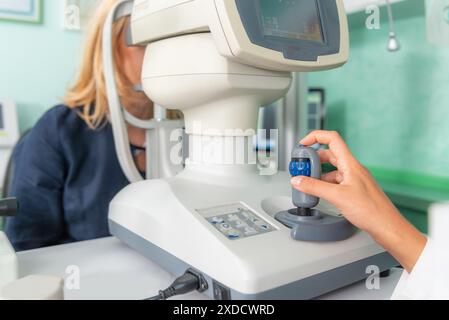 Eye examination with an auto refractometer in a professional ophthalmology setting. Stock Photo