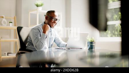 Thrilled African American businessman celebrates financial success with analyst team using laptop in modern office collaboration. Stock Photo