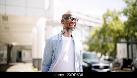 Young entrepreneur walking through urban streets, holding a laptop on his way to downtown office. Digital marketer on the go. Stock Photo