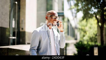 Urban entrepreneur making strategic connections outside financial institution in city, leveraging smartphone for startup success in African-American c Stock Photo