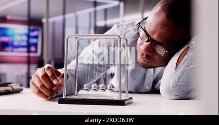 The Overworked African-American Office Manager at His Desk: a stressed man working on deadlines, multitasking on laptop. Describes office, efficiency, Stock Photo