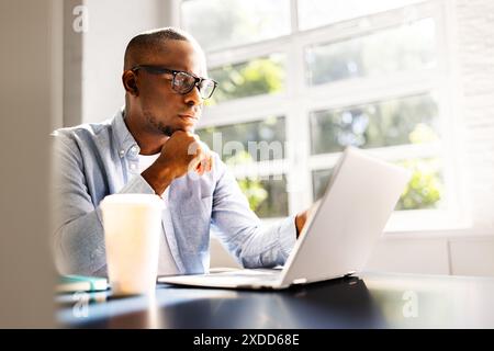 Young African American businessman studying legal cases on laptop in corporate office, developing business strategies for his law firm. Stock Photo