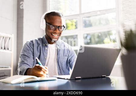 Focused Black Man Utilizing Digital Tools for Online Education in Home Office - Student, Marketer, or Journalist in Training. Stock Photo