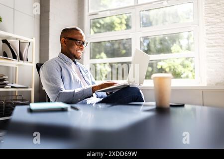Successful African American Businessman Leading Team in Analyzing Market Trends and Utilizing Technology in Modern Office Setting Stock Photo