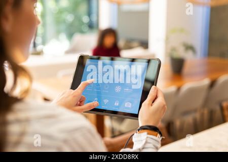 Woman using tablet to control smart home settings in living room Stock Photo