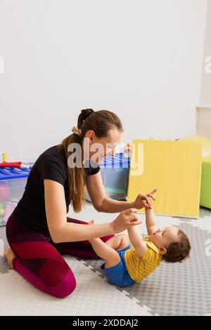 Physical therapist working with infant during neurological pediatric exam for test on newborn reflexes. Pull to sit or arm traction test Stock Photo