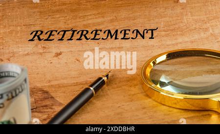Retirement concept. RETIREMENT word on papyrus in a composition with a magnifying glass, fountain pen and dollars without focus Stock Photo