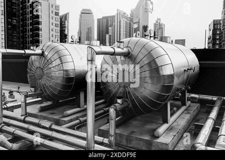 Boilers in Tank boiler hot water container delivery pipe line at roof top outdoor hotel infrastructure watering system. Stock Photo
