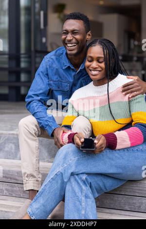 Sitting on steps, young couple smiling and enjoying time together at home Stock Photo