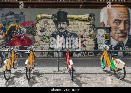 Bike sharing station in front of the  the mural 'Milan Street Hi-Story' in Via Pio IV, next to the Colonne di San Lorenzo, Milan, Lombardy, Italy Stock Photo