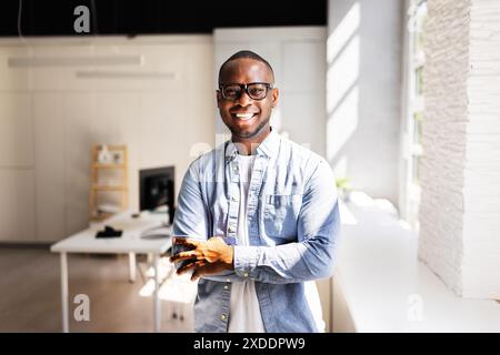Successful African American businessman standing confidently in his office, a leader in his field, a mentor to young professionals. Stock Photo