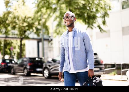 Young male corporate executive networking in bustling urban downtown, successful businessman holding portfolio on busy city street, finance entreprene Stock Photo