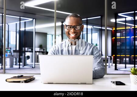 Successful African-American businessman conducts market research at modern office meeting, using laptop to analyze online data for his tech company. Stock Photo