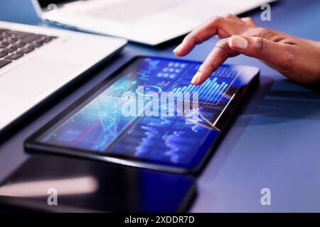 African American woman analyzing financial data on computer for business analytics dashboard in stock market brokerage firm. Stock Photo