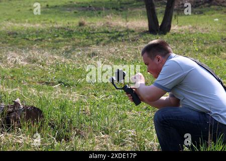 A young man videotaping on a smartphone. Uses gimbal to get smooth shots. Controls the recording by touching the screen. Stock Photo