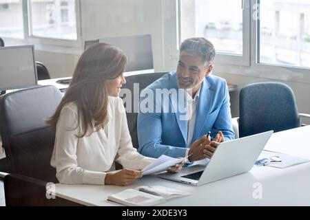 Two executives team working on laptop discussing documents at office meeting. Stock Photo