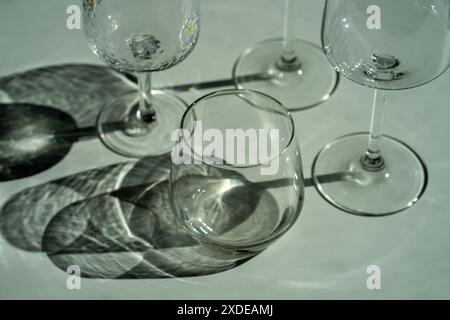 Assorted glassware for various drinks in sunlight. Stock Photo