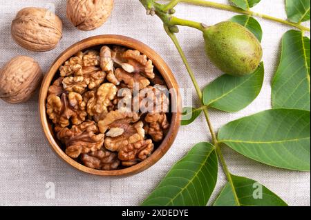 Walnut halves in a wooden bowl on linen fabric. Shelled, dried walnut kernels, ripe seeds of the common walnut tree. Stock Photo