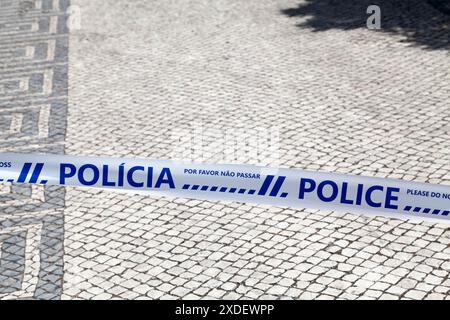 Police tape with written in it in Portuguese 'Polícia - Por favor, não passar' and English 'Police - Please, do not cross'. Stock Photo