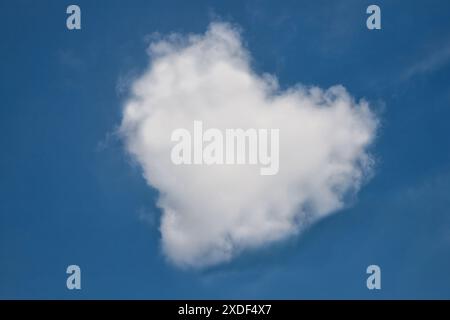 Heart shaped cloud in bright blue sky. Stock Photo