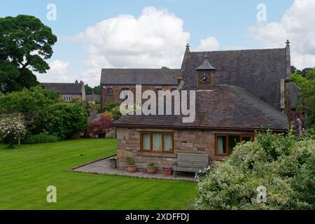 Unusual property with a clock tower on top of the extension  surrounded by trees and well maintained lawn in Biddulph, Staffordshire. June 24, 2024 Stock Photo