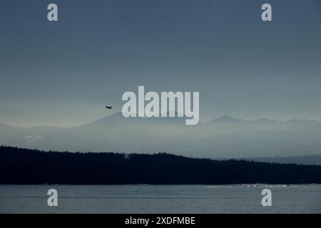 Seaplane flying over the silhouette of Mountains Stock Photo