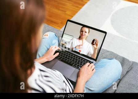 In the concept of telemedicine, a woman at home is having an online consultation with a doctor via her laptop. Stock Photo