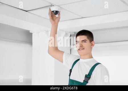 Technician installing CCTV camera on ceiling indoors Stock Photo