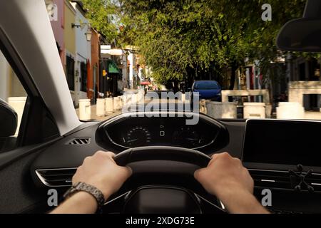 Driving car, view from driver's seat. Man holding hands on steering wheel, closeup Stock Photo