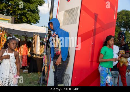 Baltimore, Maryland, USA. 22nd June, 2024. Young people stand next to an ATM machine at the AFRAM (African-American Food, Music, Arts and Crafts) festival, Saturday, June 22, 2024 in Baltimore, Maryland. Baltimore reached 101 degrees, breaking the previous record high for the date of 100 set in 1988. (Eric Kayne/Zuma Press Images) @photokayne (Credit Image: © Eric Kayne/ZUMA Press Wire) EDITORIAL USAGE ONLY! Not for Commercial USAGE! Stock Photo