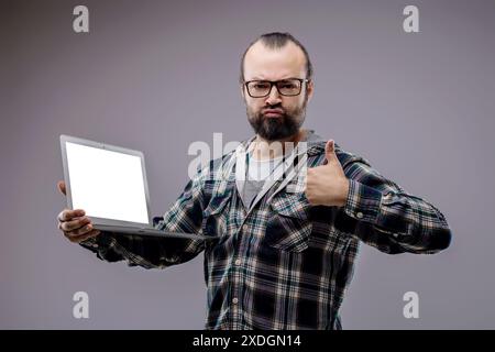 Web developer is holding a laptop with a blank screen and giving a thumbs up of approval for internet security and computer science Stock Photo