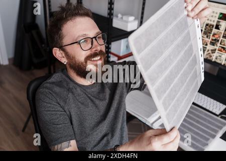Photographer reviewing film negatives in a modern studio Stock Photo