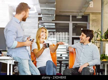 Young friendly colleagues talking and laughing in office Stock Photo