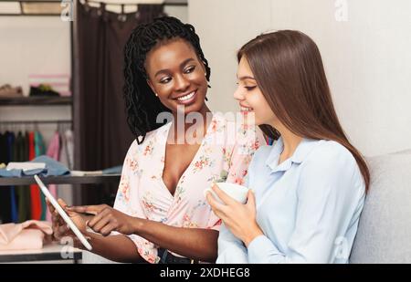 Two Women Standing Next to Each Other Looking at Tablet Stock Photo