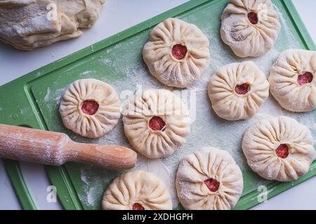Semi-finished homemade belyashi or meat open pies on a green cutting board with a rolling pin. High quality photo Stock Photo