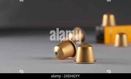 Gold coffee capsules arranged near a box on a gradient background, modern packaging Stock Photo