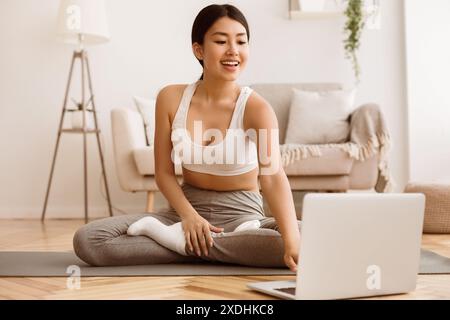 Woman Practicing Yoga at Home With Laptop Stock Photo
