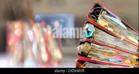 messy file folders and business records ,red tape, bureaucracy,overworked,beat the clock business concept on blurred office background. Stock Photo