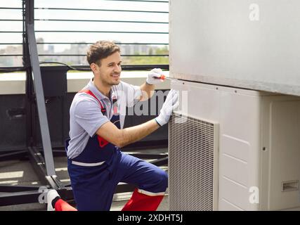 Electrician Installing, Servicing, Or Repairing Hvac System On Roof Stock Photo