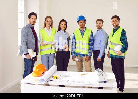 Team of architects, engineers and builders standing by office table with construction plans Stock Photo