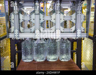 Machine moving 5 litre water bottles in warehouse. Stock Photo