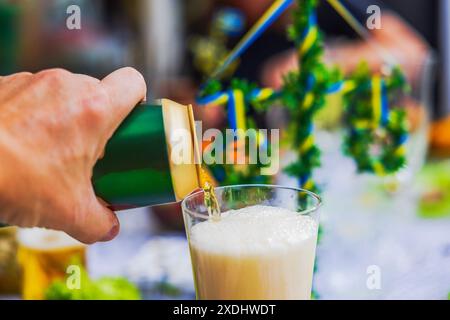 Close-up view of man's hand pouring beer from can into glass at festive table. Stock Photo