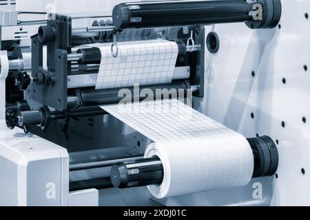 A roll of white paper is passed through the machine. printer and sticker machine, which is used for printing and applying stickers to packaging indust Stock Photo