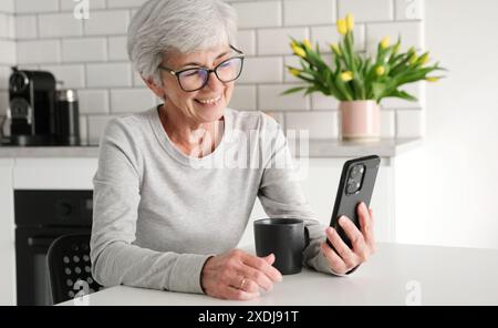 Cheerful Elderly Lady Video Calls Using A Messaging App Stock Photo