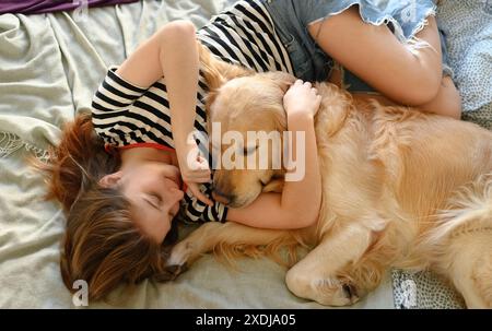 Girl lying on a bed with her golden retriever dog Stock Photo - Alamy