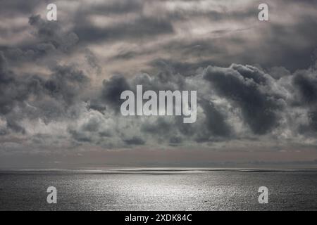 Before a storm, these incredible clouds formed over the sea. The sun's rays pass through them but are unable to change the grey color of the sea Stock Photo