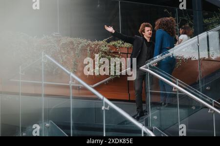 Businesspeople having misunderstanding, engaging in conversation on modern glass staircase Stock Photo