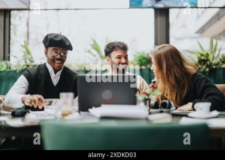 Multiethnic team members are deeply involved in a business discussion at a cafe, with laptops and documents spread on the table. Stock Photo
