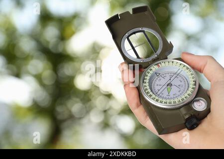 Woman holding compass in nature, closeup. Navigational instrument Stock Photo